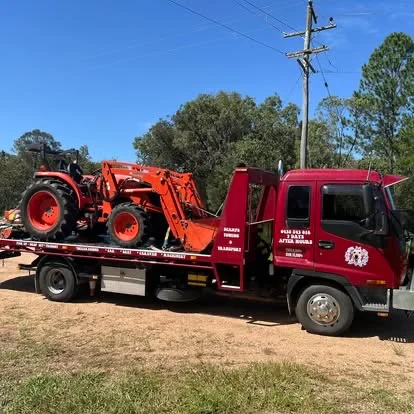 Red tractor loaded on red tow truck in FNQ