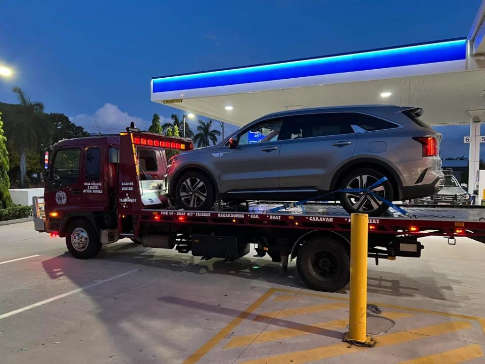 Modern SUV on red tow truck at night